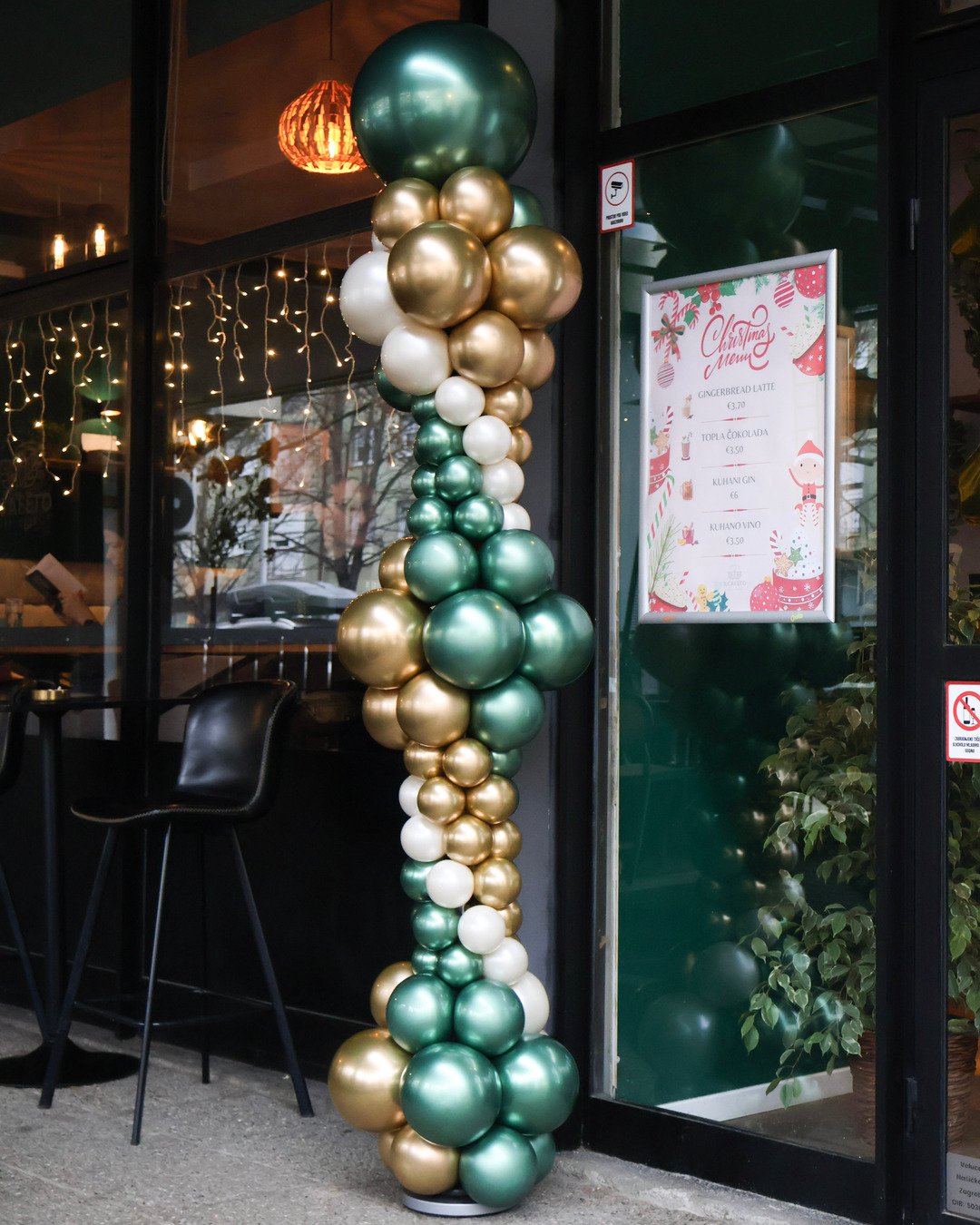 Elegantni balonski stup u organskom stilu s kromiranim smaragdno zelenim i zlatnim balonima, idealan kao ulazna dekoracija za kafiće, restorane i poslovne evente u Zagrebu, Joli Spot.