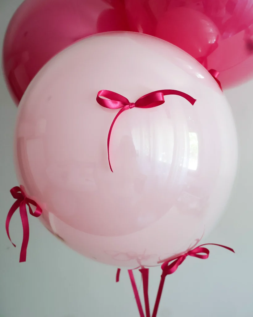 Rozi jumbo balon od 18 inča obučen u prozirni bobo balon ukrašen fuksija rozim mašnama